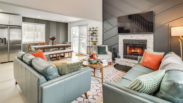 A modern living room with a fireplace, grey sofas, and a dining area with a table and chairs. - All-Season Fun! Tobyhanna Getaway w/ Lake Access (Tobyhanna)