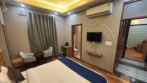 Une chambre d’hôtel équipée d’un lit, d’un bureau, d’une chaise, d’un téléviseur fixé au mur et d’un appareil de climatisation.