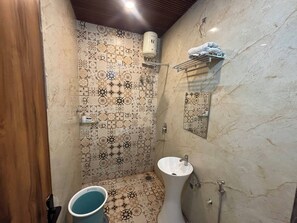 Un baño con pared de azulejos estampados, un lavamanos blanco y una zona de ducha.