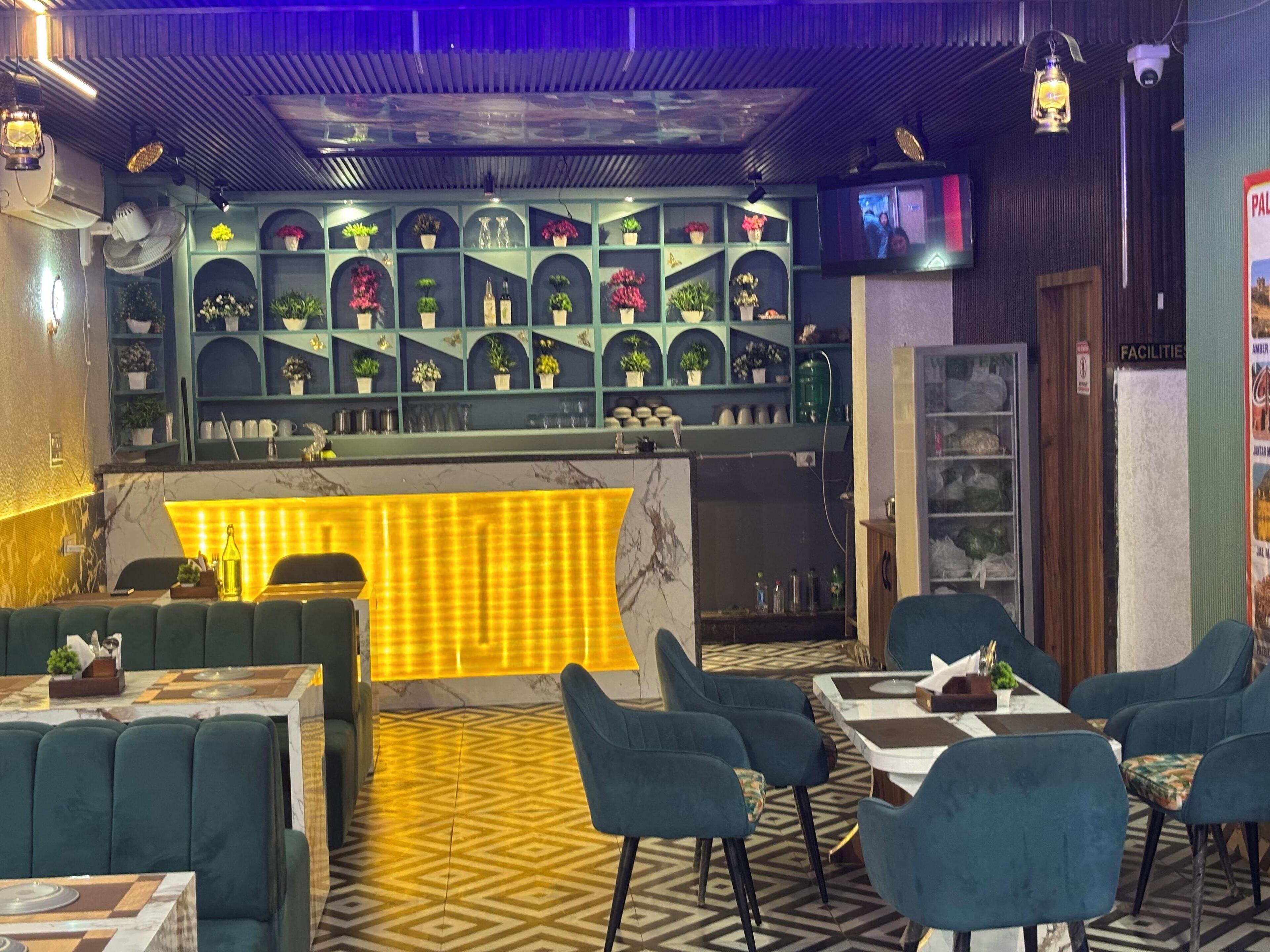 Un restaurant doté d’un bar, de sièges verts et d’un sol à motifs.