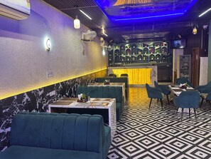Un restaurante con asientos tapizados en verde, una pared de mármol y un suelo con estampado.