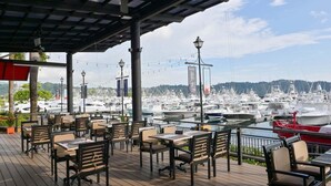 An outdoor seating area with tables and chairs, overlooking a marina with numerous boats. - Montebello 1E 3 bdr Ocean View in Los Suenos (Jacó)