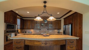 A spacious kitchen with a large island, wooden cabinetry, a built-in microwave, and a stainless steel refrigerator. - Montebello 2E 3 bdr Ocean View in Los Suenos (Jacó)