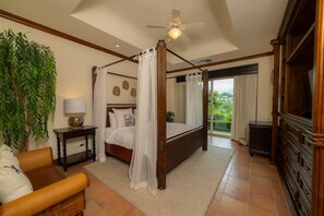 A four-poster bed with a canopy, a television, a large plant, and a view of the outdoors. - Montebello 4E 3 bdr Pool View in Los Suenos (Jacó)