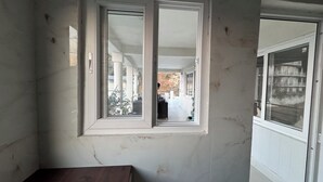 A room with a large window, a door, and a visible balcony area. - Pahadi Pind Homestay 2BR Mukteshwar - Mountain View (Mukteshwar)