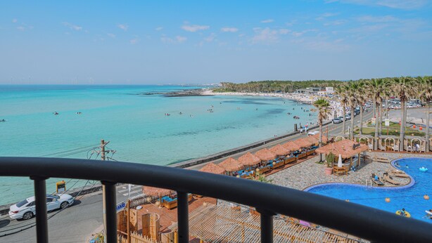 A coastal hotel with a pool, beach view, and thatched-roof umbrellas. - Geumneung inn (Jeju City)