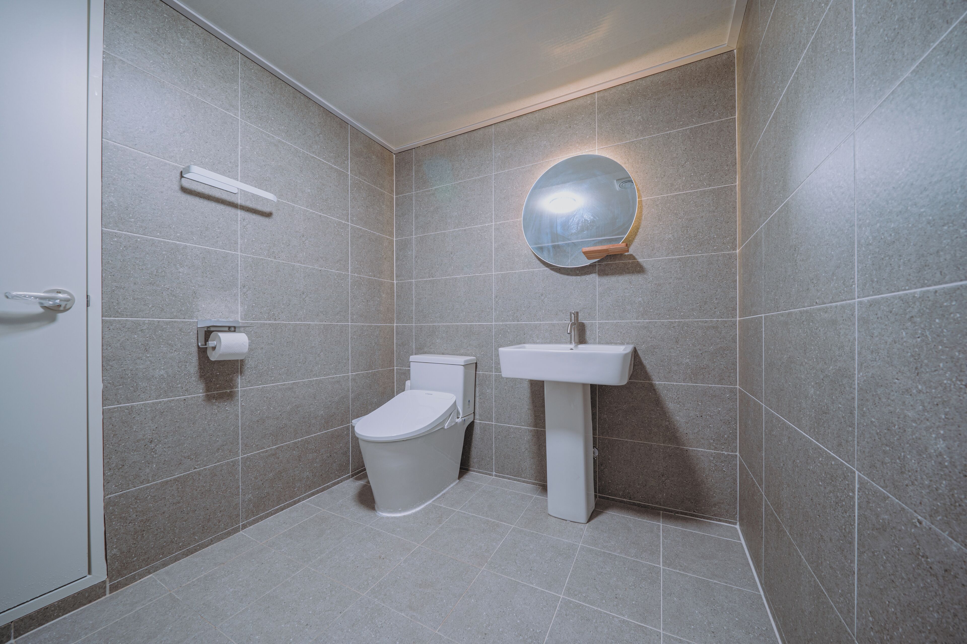 A bathroom with a toilet, sink, and mirror.