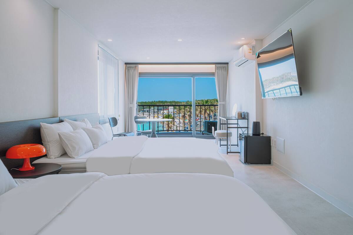Ein modernes Hotelzimmer mit Balkon, Bett, Schreibtisch und Fernseher.