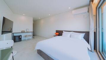 A modern hotel room with a large bed, a desk, a chair, and a TV.