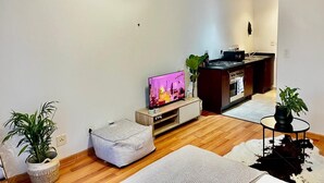 A modern living room with a flat-screen TV, a kitchen area, and a dining table. - Stay Central. Stay Comfortable. Work & Play in JHB central (Johannesburg)