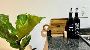 A kitchen counter with a wooden cutting board, two bottles labeled "OIL" and "VINEGAR," and a potted plant. - Stay Central. Stay Comfortable. Work & Play in JHB central (Johannesburg)