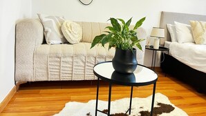 A modern living room with a sofa, a round coffee table with a potted plant, a white shag rug, and a framed picture on the wall. - Stay Central. Stay Comfortable. Work & Play in JHB central (Johannesburg)