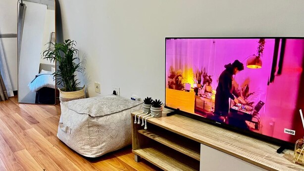A modern living room with a flat-screen TV, a wooden entertainment unit, a bean bag, a potted plant, and a mirror on the wall. - Stay Central. Stay Comfortable. Work & Play in JHB central (Johannesburg)