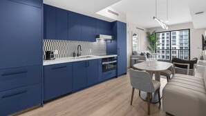 Una cocina moderna con armarios azules, una encimera blanca y una zona de comedor con una mesa redonda y sillas.