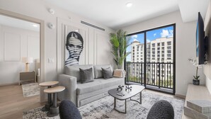 Una sala de estar moderna con un sofá gris, una mesita de centro y un ventanal con vistas a un edificio.