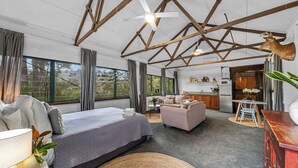 Een ruime kamer met een groot bed, een bank, een eettafel en een keukenhoek.