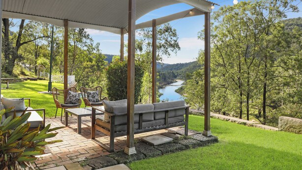 Een overdekt terras met uitzicht op een rivier en heuvels.