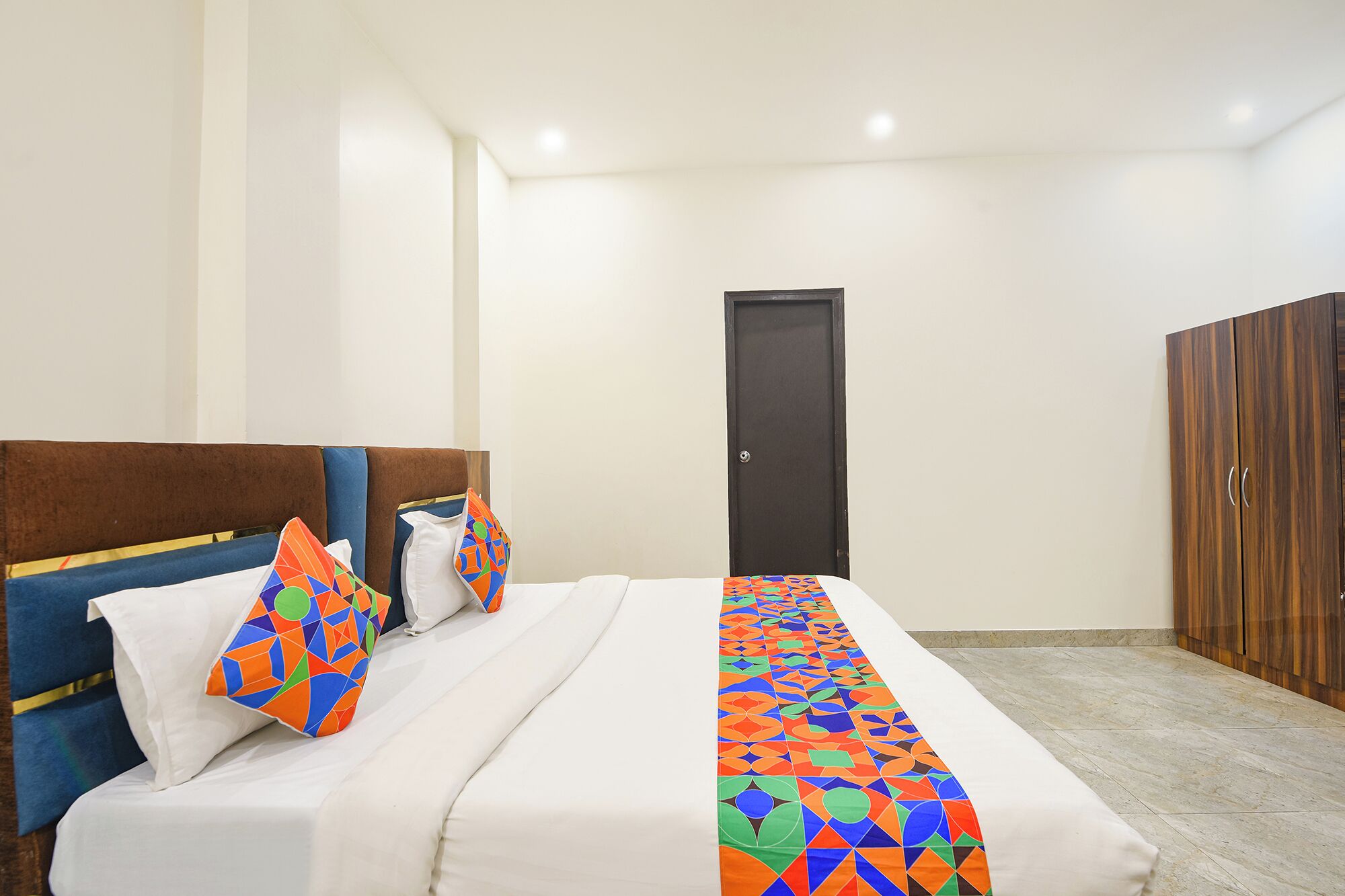 A hotel room with a bed, a door, and a wardrobe.