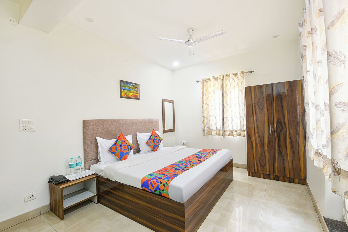 A hotel room with a bed, a nightstand, a ceiling fan, a window with curtains, and a wardrobe.
