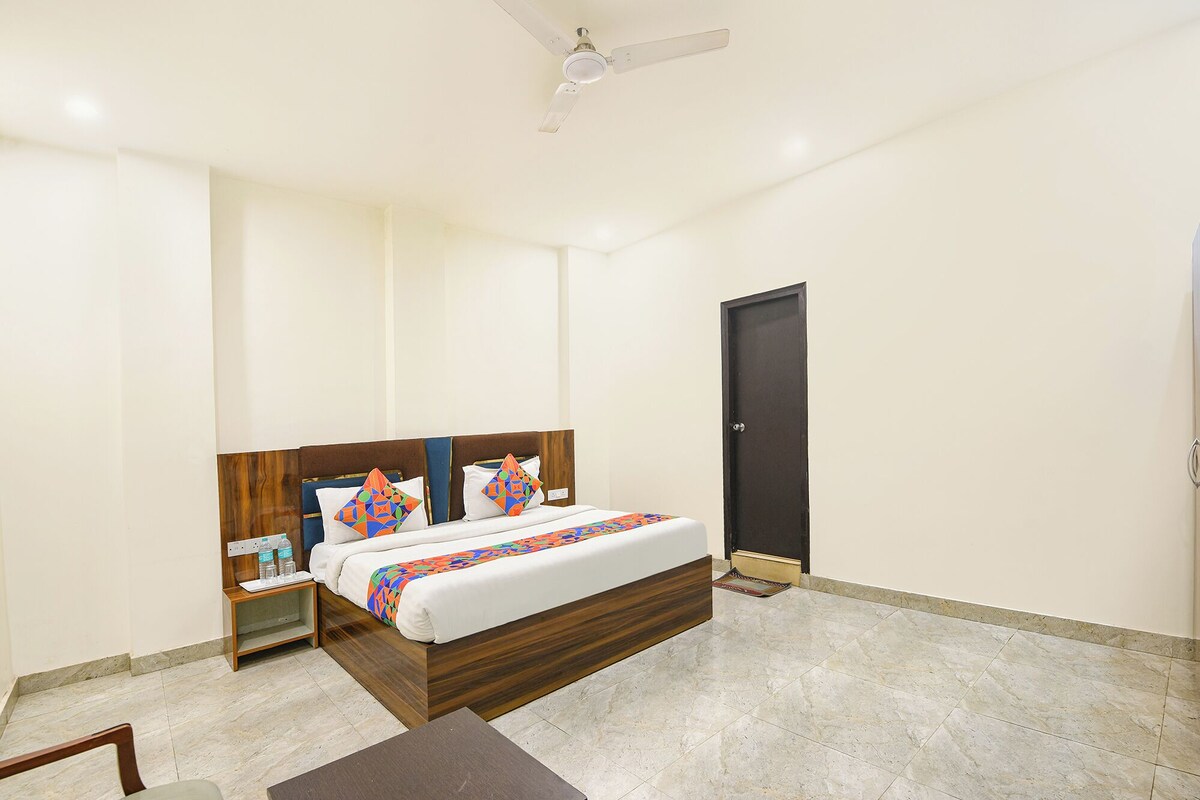 A bedroom with a bed, nightstands, a desk, a chair, a door, and a ceiling fan.