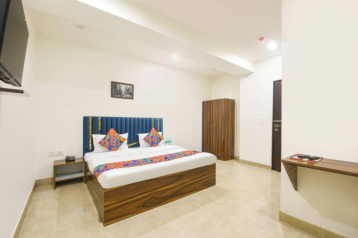 A hotel room with a bed, a wardrobe, a bedside table, and a desk.