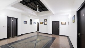 A hallway with black doors, white walls, and a ceiling fan. - Fabhotel Fortune Residency - Nr Sarai Rohilla Railway Station (New Delhi)