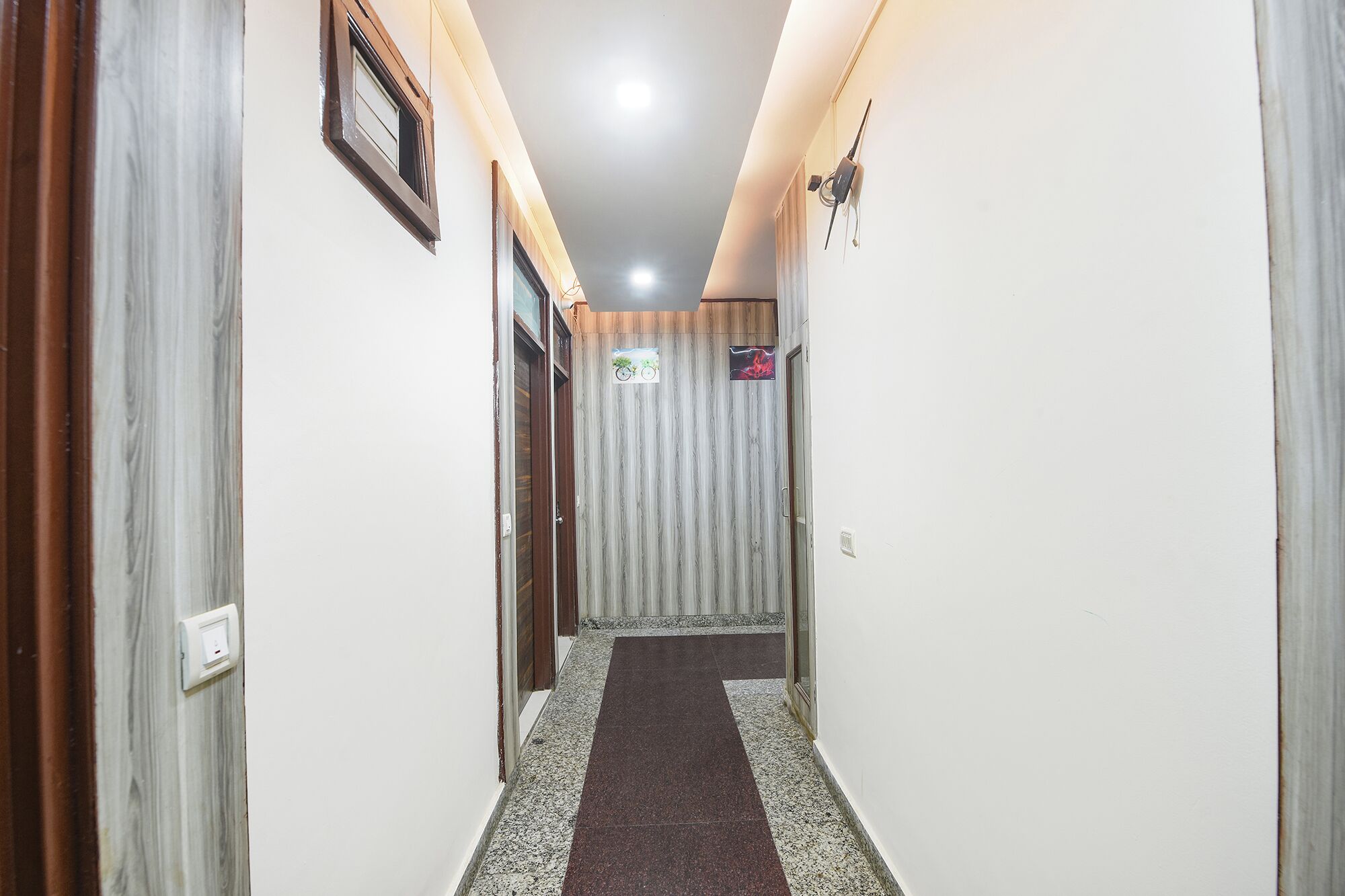 Un couloir avec un sol à motifs, des portes et un luminaire fixé au mur.