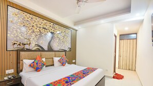 A modern hotel room with a bed, a nightstand, a wall-mounted artwork, and a ceiling fan. - Fabhotel Lookout Stay (New Delhi)