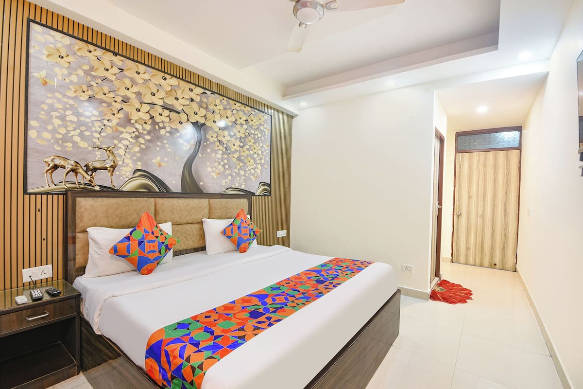 A modern hotel room with a bed, a nightstand, a wall-mounted artwork, and a ceiling fan.