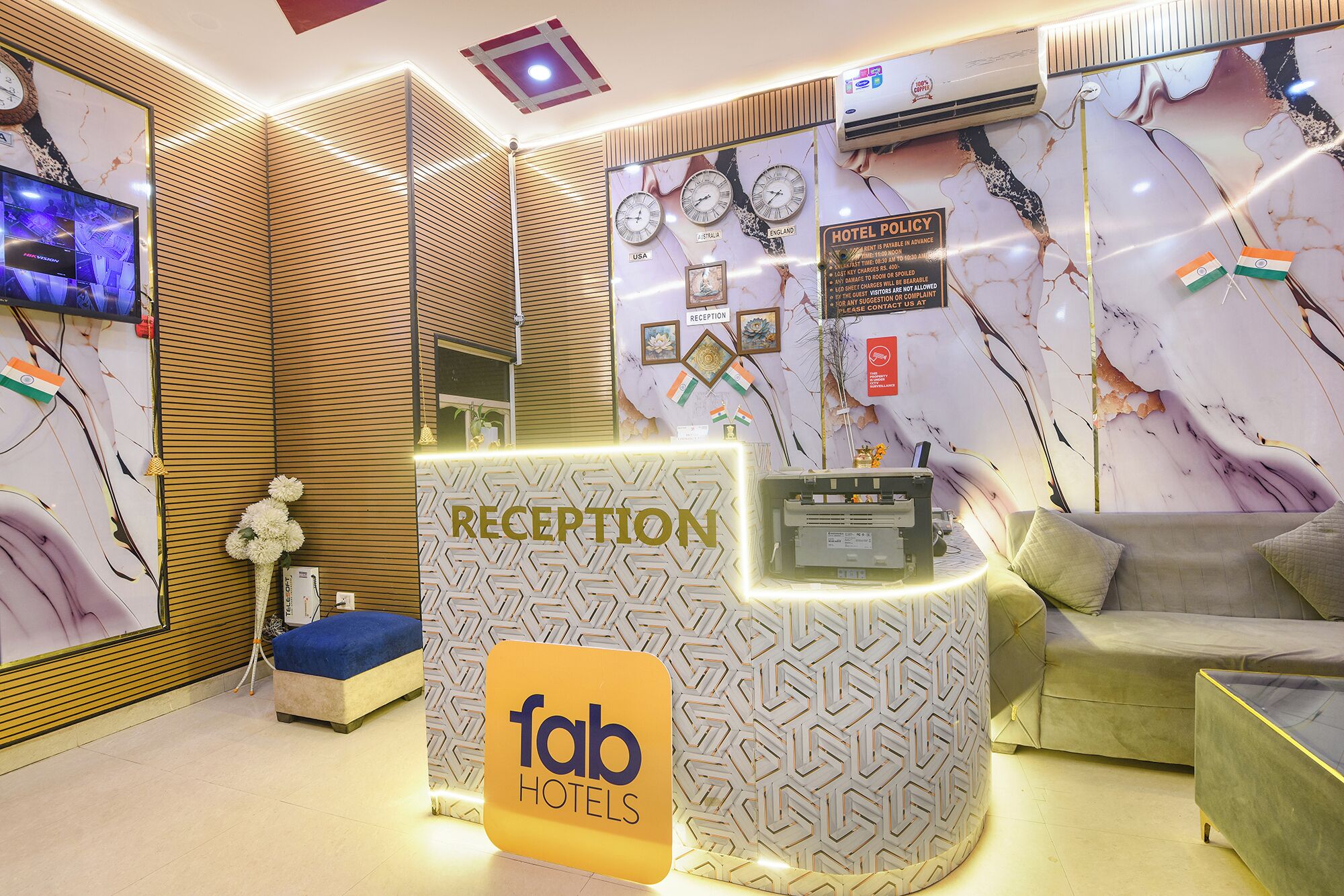 A reception area with a reception desk, a sofa, and a wall with clocks and flags.
