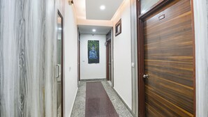 A hallway with a wooden door labeled '102', a framed picture on the wall, and a marble-like wall on the left. - Fabhotel Lookout Stay (New Delhi)