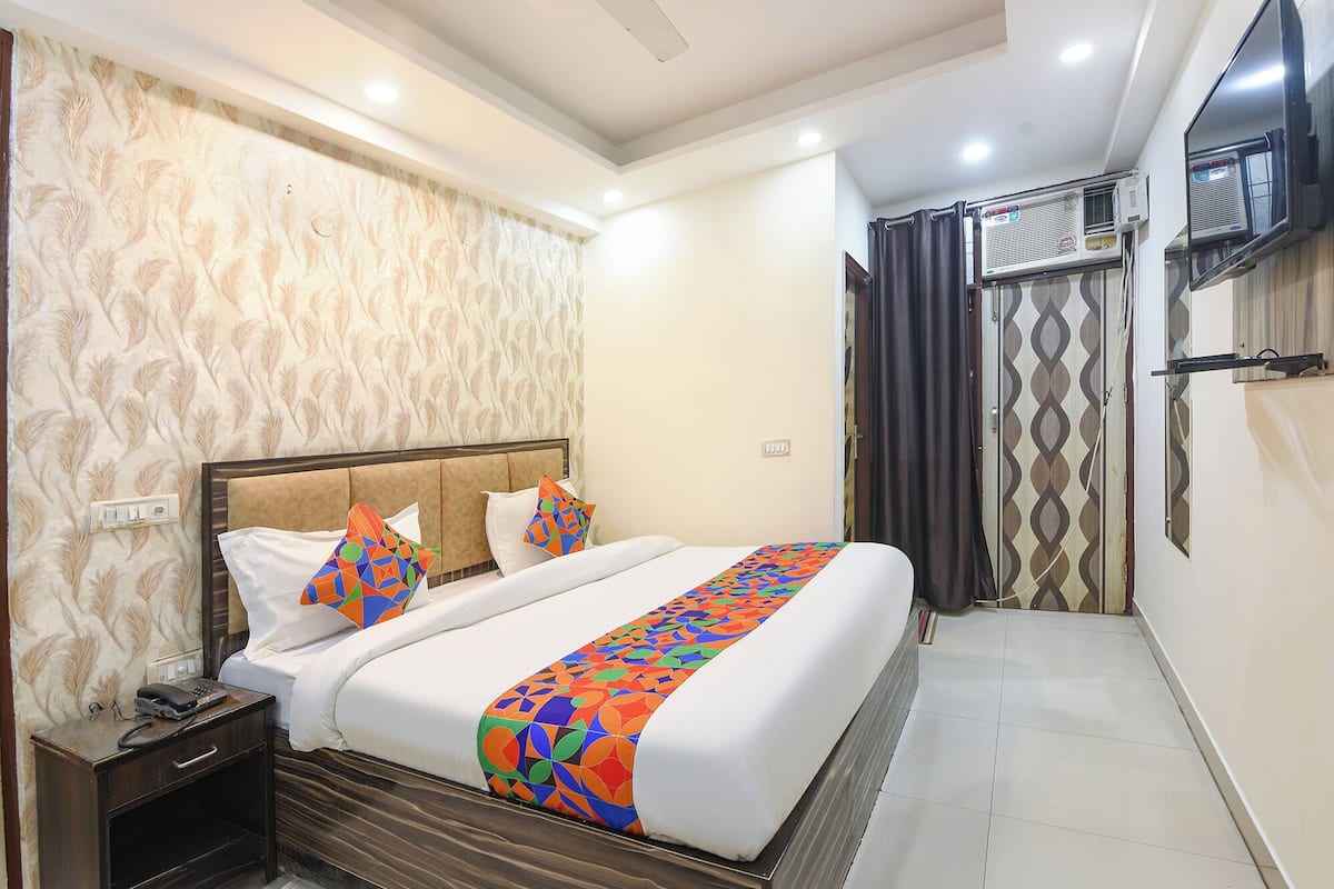 A hotel room with a bed, nightstand, and a television mounted on the wall.