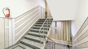 A staircase with metal railings, a fire extinguisher mounted on the wall, and a potted plant at the bottom. - Fabhotel Lookout Stay (New Delhi)