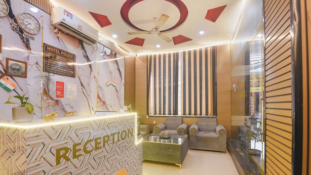 A reception area with a marble wall, a ceiling fan, and a sofa. - Fabhotel Lookout Stay (New Delhi)