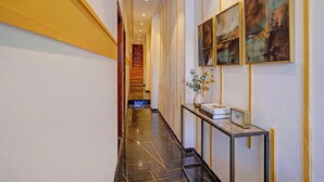 A hotel hallway with a polished black marble floor, a console table with a vase and clock, and abstract paintings on the walls. - Fabhotel Beverly Plaza (Mumbai)