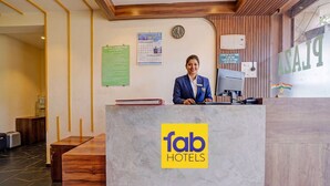 A reception desk with a 'fab hotels' logo, a clock, a calendar, and a sign indicating check-out time. - Fabhotel Beverly Plaza (Mumbai)