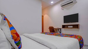 A hotel room with a bed, a chair, a desk, and a flat-screen TV mounted on the wall. - Fabhotel Beverly Plaza (Mumbai)