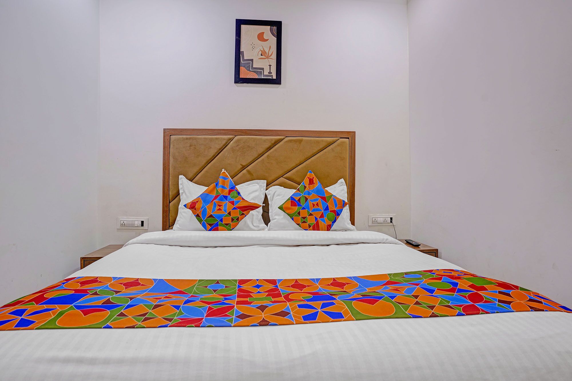 Un lit avec une couvre-lit à motifs géométriques et deux oreillers aux motifs similaires.