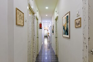 A hallway with framed artwork on the walls, a fire extinguisher mounted on the wall, and a door at the end. - Fabhotel Demattrie Budget (Kolkata)