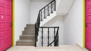 A staircase with a black wrought iron railing, beige steps, and two bright pink doors with the number '5' on one. - Fabhotel Boutique Stays Lake Pichola (Udaipur)