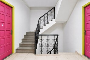 A staircase with a black wrought iron railing, beige steps, and two bright pink doors with the number '5' on one. - Fabhotel Boutique Stays Lake Pichola (Udaipur)