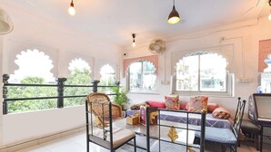 A room with a bed, two chairs, a table, and a window with decorative shutters. - Fabhotel Boutique Stays Lake Pichola (Udaipur)