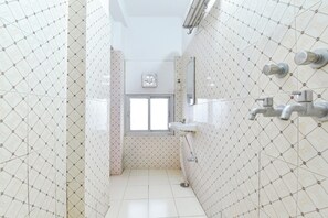 Une salle de bain avec des carreaux décorés, une fenêtre, un lavabo et un miroir.