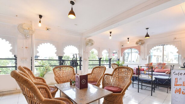 A room with wicker furniture, a table, and a balcony with a view. - Fabhotel Boutique Stays Lake Pichola (Udaipur)
