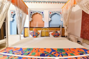 Ein Bett mit geometrisch gemustertem Überwurf, einem gesteppten Kopfteil und dekorativen Wandverkleidungen.