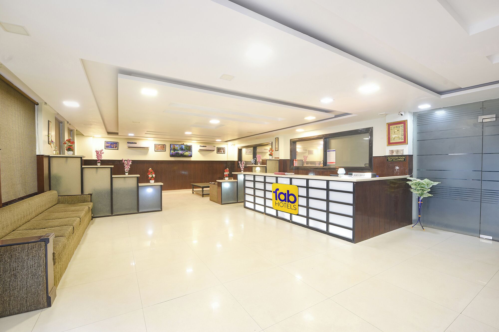 A hotel reception area with a reception desk, seating area, and a large mirror.