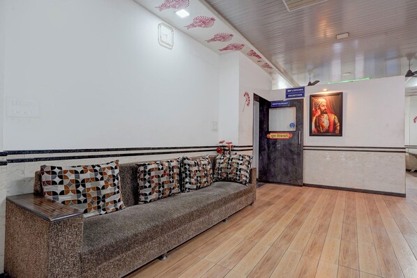 A reception area with a sofa, a framed portrait, and directional signs for lodging, reception, and restaurant. - Fabhotel Raj (Bhor)