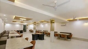 Un comedor amplio con varias mesas y sillas, ventiladores de techo e iluminación empotrada.