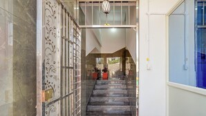 A staircase leading to a second floor with a decorative metal gate on the left and a blue window on the right. - Via Guru Residency - Kengeri (Bangalore)