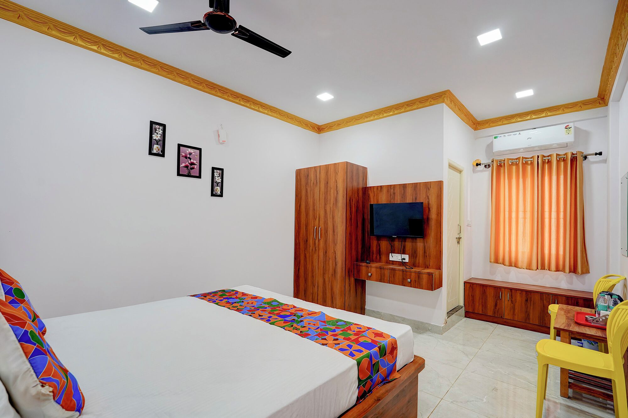 Un dormitorio con dos camas, televisión, armario de madera y baño con cortina naranja.